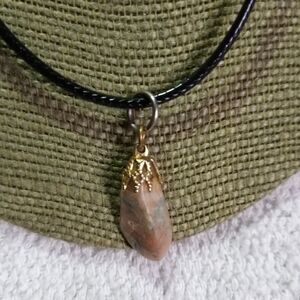 Goldtone pinkish rock pendant on black cord necklace